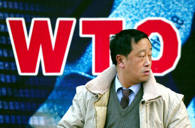 A man walks past a billboard which celebrates China's accession into the World Trade Organization in Beijing, 9 December 2002 (Photo: AP Photo/Greg Baker).