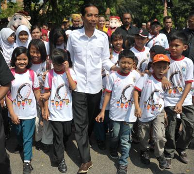 Jakarta governor Joko Widodo walks with school children during sight inspection of city projects in Jakarta, 22 August 2013. (Photo: AAP)