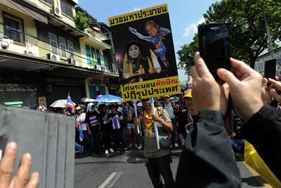 A Thai opposition protester holds up a placard showing protest leader Suthep Thaugsuban hitting prime minister Yingluck Shinawatra during a rally at the Interior Ministry in Bangkok on 1 December 2013. (Photo: AAP)