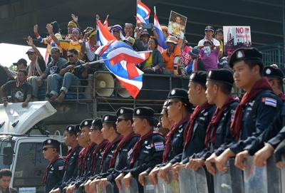Thai anti government protesters wave national flags next to riot police during a demonstration at Army Club in Bangkok on 10 December 2013. (Photo: AAP)