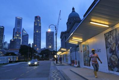 A foreign construction worker from Bangladesh walks past Singapore's city hall with the Singapore skyline in the background, 16 December 2013. (Photo: AAP)