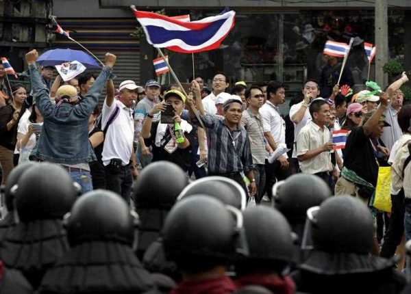 Thousands of anti-government protesters march in front of anti-riot policemen on a main road during a massive rally in central Bangkok, Thailand, 11 November 2013. (Photo: AAP)