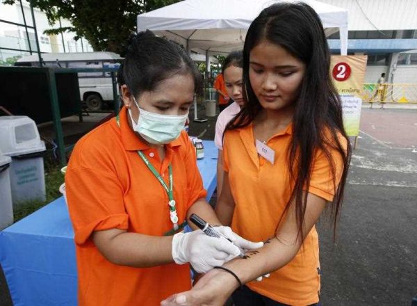 A foreign worker is given medicine and marked on her arm during a health check at a foreign workers registration one stop service post for Cambodia, Myanmar and Laos nationals, in a park in Bangkok, Thailand, 16 July 2014. (Photo: AAP)