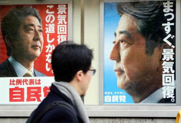 A man walks past posters of Japanese prime minister and ruling Liberal Democratic Party (LDP) leader Shinzo Abe displayed at the LDP headquarters in Tokyo on 4 December 2014. (Photo: AAP).