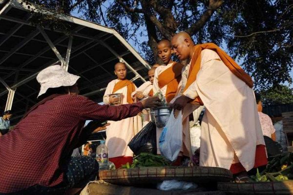 Street vendors offer vegetables to Buddhist monks near a train station on the outskirts of Yangon, Myanmar, 12 December 2014. (Photo: AAP).