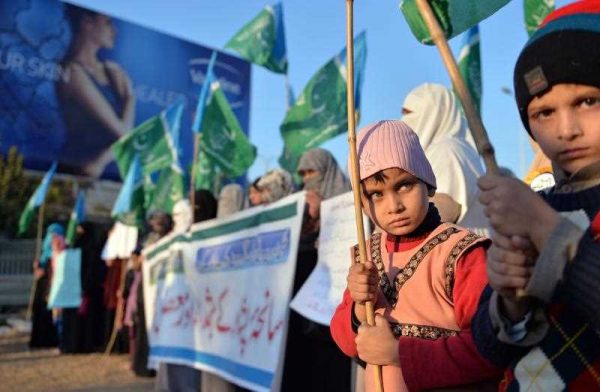 Children hold flags as women supporters of Pakistani political and Islamic party Jammat-e-Islami stage a protest against the Taliban militants attack on an army-run school in Peshawar, Islamabad, 26 December 2014. (Photo: AAP).