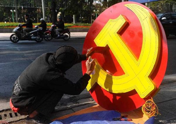 A Vietnamese worker paints a communist sign before hanging it over a street as decoration prior to New Year celebrations in Hanoi on 22 December 2014. (Photo: AAP).