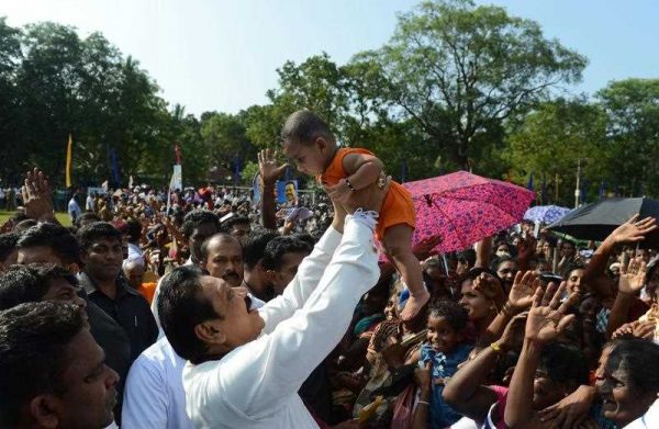 Sri Lanka's President Mahinda Rajapaksa holds a baby as he meets with supporters ahead of the upcoming midterm election, Vavuniya, 2 January 2015. (Photo: AAP).