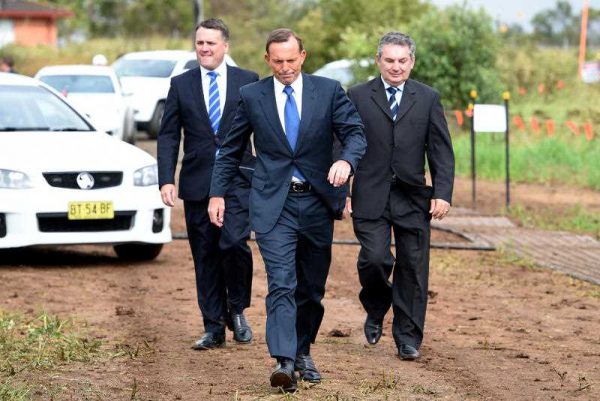 Prime Minister Tony Abbott, is greeted by Assistant Minister for Infrastructure and Regional Development, Jamie Briggs, and Federal member for Macarthur Russell Matheson, as he arrives to announce the start of the upgrade to Bringelly road, in Sydney, 20 January 2015. The Australian government’s focus on putting its budget on a ‘credible path back to surplus’ over the medium term, appears to rule out any substantial infrastructure investment program as a form of stimulus. (Photo: AAP).