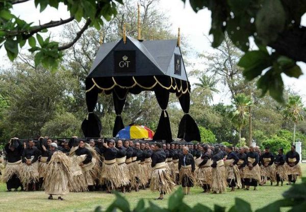 Hundreds of pall bearers, all wearing black clothes and traditional woven ta'ovala mats around their waists, carry the royal standard draped casket of King George Tupou V on a black and gold catafalque from the Royal Palace at the start of the king's funeral procession through the capital Nuku'alofa on 27 March 2012. (Photo: AAP)