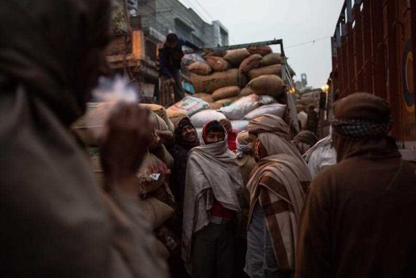 Indian labourers wait to unload goods from trucks at a market in New Delhi on 28 January 2015. (Photo: AAP).