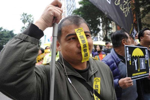 A pro-democracy protester, putting a yellow sticker reading 