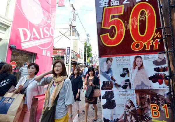 his photograph taken on 27 September 2013 shows shoppers walking past displays offering clothing on sale in Tokyo's Harajuku shopping district. (Photo: AAP)