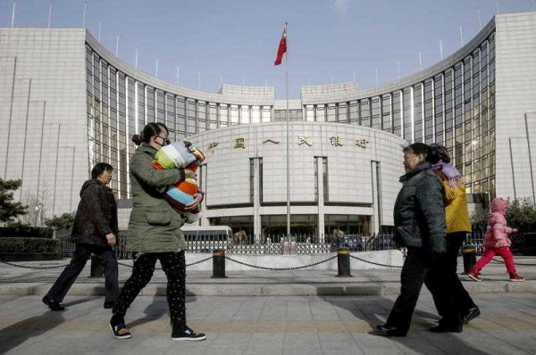 Pedestrians walk past the head office of the People's Bank of China (PBoC), China's central bank, in Beijing. (Photo: AAP).