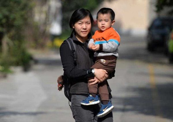A mother carries her son on a street in Shanghai on 16 November 2013. Days after a key meeting in Beijing the Communist leadership announced that it would allow couples to have two children if one parent is an only child, widening the exemptions from a rule imposed in the late 1970s to control China's population. (Photo: AAP).