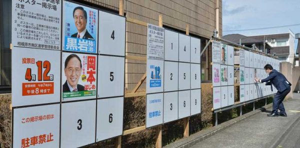 A campaign staff puts up posters for candidates in local assembly elections in Sagamihara, Kanagawa Prefecture on 3 April 2015. (Photo: AAP)