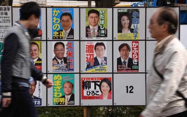 People walk past posters of candidates for the Kawasaki City Assembly in Kawasaki, suburbun Tokyo, on 12 April 2015. The nationwide local elections were partially seen as a referendum on Prime Minister Shinzo Abe's efforts to boost the country's economy with upper house elections due next year. (Photo: AAP).