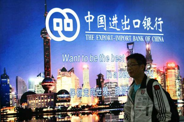 A pedestrian walks past an advertisement for The Export-Import Bank of China in Shanghai, China, 4 November 2014. (Photo: AAP)