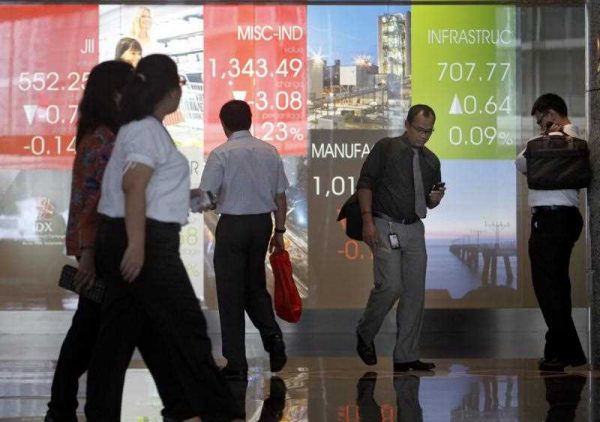 Indonesian walk pass the trade monitor at Indonesia Stock Exchange in Jakarta, Indonesia. (Photo: AAP)