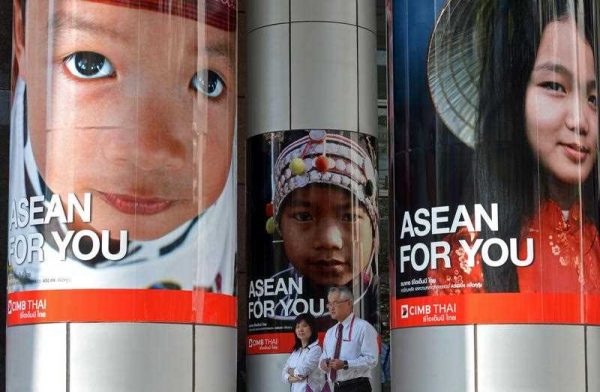Thai office workers walk past advertising promoting the ASEAN Economic Community in Bangkok on 13 January 2013. The AEC is unlikely to be ready by its deadline. (Photo: AAP)