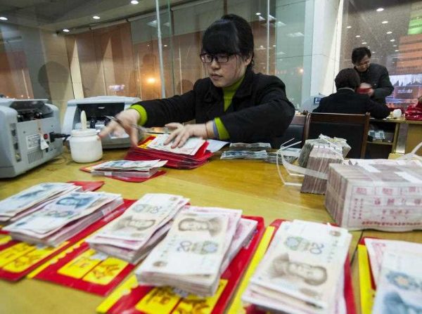 A Chinese clerk counts RMB (renminbi) yuan banknotes at a branch of China Construction Bank, 15 February 2015. In 2014, China became a net capital exporter for the first time. (Photo: AAP)