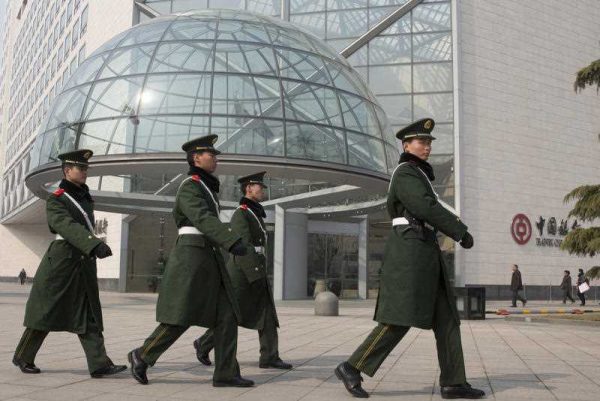 Paramilitary police patrol near the headquarters of the Bank of China in Beijing, 7 March 2015. The Xi administration has implemented a flagship policy to thoroughly clean up corruption in China. (Photo: AAP).