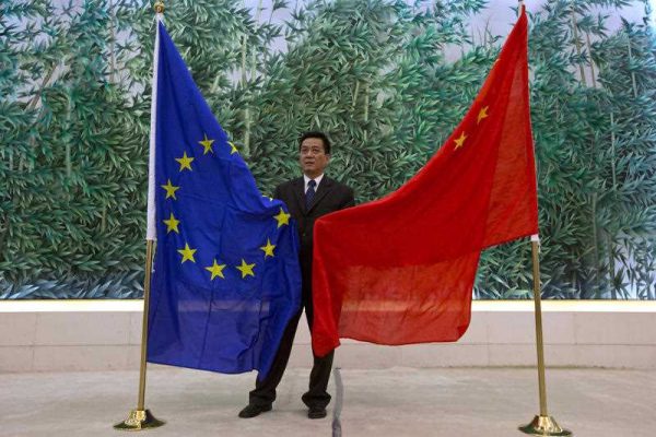 A Chinese Trade Ministry officer prepares the EU and Chinese flags prior to a joint reading of statements by the EU and China in 2013. (Photo: AAP)