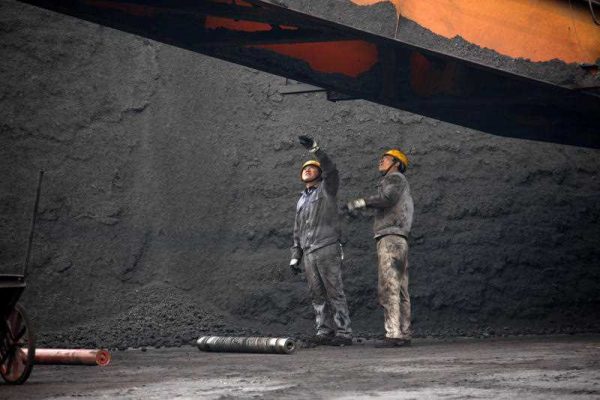 Chinese workers examine piles of coal at a plant in Huaibei City, China, 7 March 2014. (Photo: AAP).
