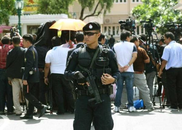 A Thai policeman stands guard as Prime Minister Prayut Chan-o-cha speaks to members of the media at Government House in Bangkok one year after the 2014 military coup, 22 May 2015. (Photo: AAP).