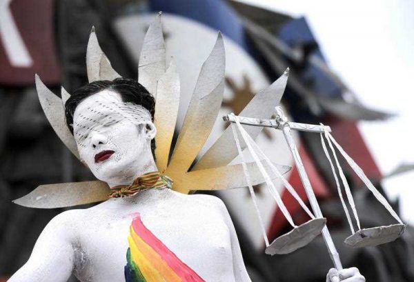 A Filipino protester from a gay and lesbian activist group mocks 'Lady Justice' in a rally calling for the resignation of Philippine President Benigno Aquino III, 24 July 2014. The group condemned the social injustices caused by the Aquino regime. (Photo: AAP)