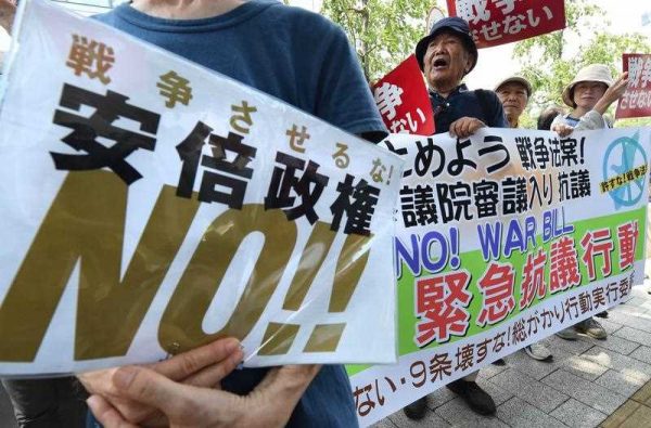 People shout slogans as they hold a banner during a rally to protest against controversial security bills which would expand the remit of the country's armed forces, in front of the National Diet in Tokyo on 27 July 2015. (Photo: AAP)