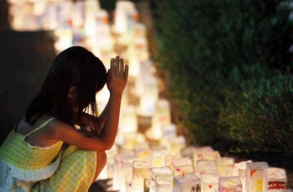A girl offers a prayer for A-bomb victims before lanterns placed at the Peace Memorial Park in Nagasaki, Japan's southern island of Kyushu on 8 August 2015. (Photo: AAP)
