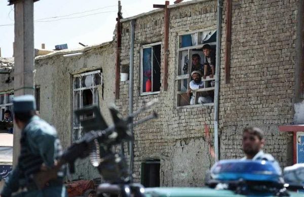 Afghan residents watch as security forces keep guard at the site of a huge blast near the entrance of the international airport, in Kabul on August 10, 2015 (Photo: AAP)
