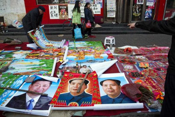 Vendors sell posters of Chinese President Xi Jinping and Communist Party founder Mao Zedong on a street of Gujiao in northern China's Shanxi province. (Photo: AAP)