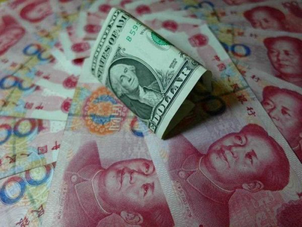 Yuan banknotes and US dollars are seen on a table in Yichang, central China's Hubei province on August 14, 2015. (Photo: AAP)