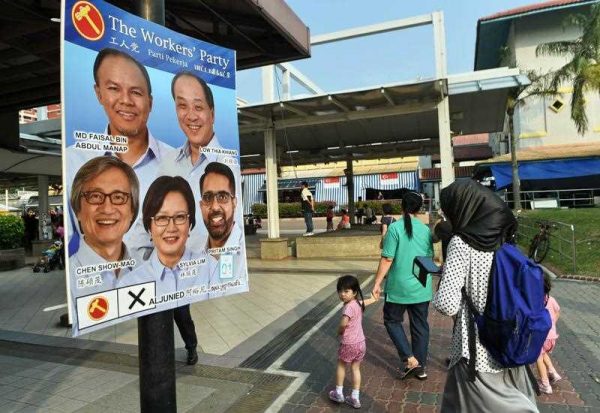 Residents walk past an election candidates poster of the opposition Worker's Party (WP) in Aljunied GRC at Hougang in Singapore on 5 September 2015, ahead of Singapore's 11 September election. (Photo: AAP)