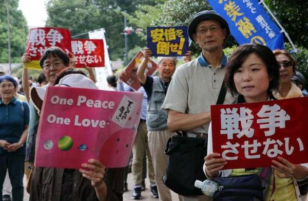 People hold placards to protest against Japan's Prime Minister Shinzo Abe's controversial security bills near the National Diet in Tokyo on 19 September 2015. (Photo: AAP)
