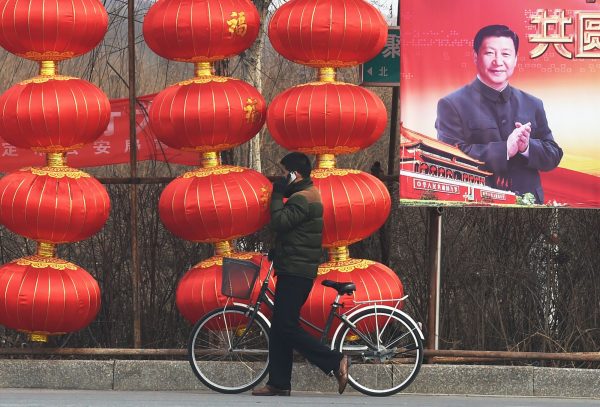 A man walks past a billboard featuring a photo of Chinese President Xi Jinping beside lantern decorations for the Lunar New Year in Baoding, China's northern Hebei province on 24 February 2015. (Photo: AFP)