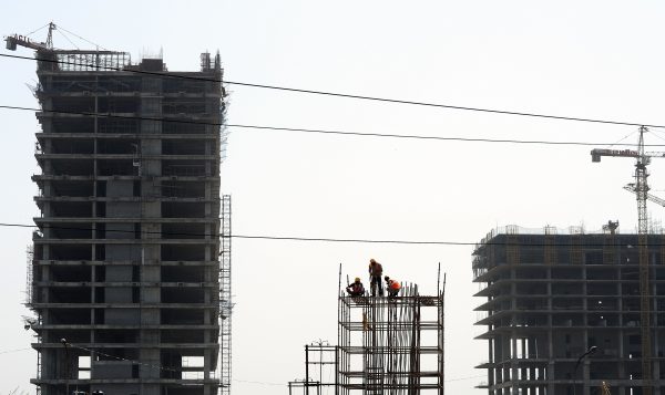 Indian workers work on a construction site on the outskirts of New Delhi on March 9, 2015. India's government has announced an $11.3-billion increase in spending on roads, rail and other infrastructure (Photo: AAP).