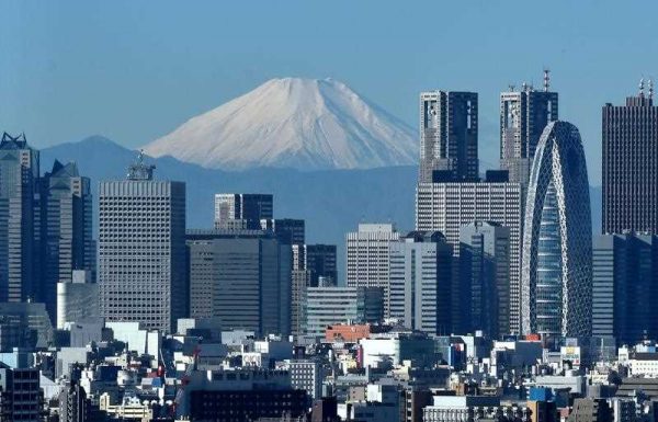 Japan's highest mountain, Mount Fuji is seen behind the skyline of the Shinjuku area of Tokyo on 6 December 2014. (Photo: AAP)