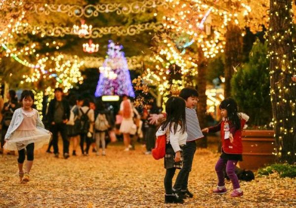 Children scatter autumn leaves into the air at dusk in Tokyo, Japan, 21 November 2015. (Photo: AAP)