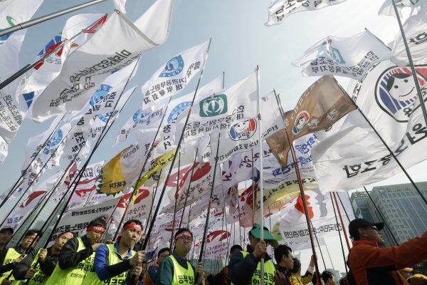 Unionised civil servants hold their union flags during a rally to oppose the government's bid to overhaul the public pension system near the National Assembly in Seoul, South Korea, 28 March 2015. South Korean President Park Geun-hye called for parliamentary endorsement of a bill meant to reform the pension system for civil servants in the latest appeal to reduce the government's growing pension deficit. (Photo: AAP)
