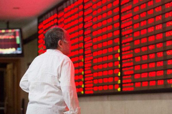 A Chinese investor looks at prices of shares (red for price rising) at a stock brokerage house in Nanjing, China, 23 October 2015. (Photo AAP).