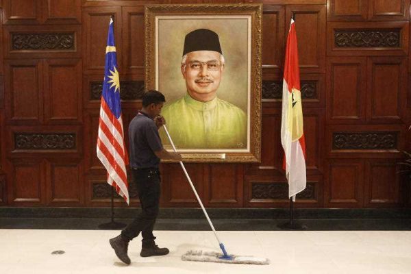 A maintenance worker works near a portrait of Malaysian Prime Minister Najib Razak during the 69th United Malays National Organisation general assembly in Kuala Lumpur, Malaysia, 8 December 2015. (Photo: AAP).