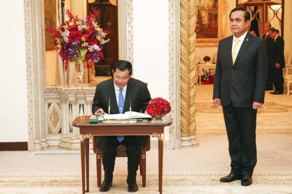 Cambodian Prime Minister Hun Sen signs a guest book as his Thai counterpart stands at Government House in Bangkok, Thailand, 18 December 2015. (Photo: AAP).