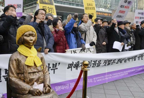 People protest a recent landmark deal between Japan and South Korea over women forced to work in Japan's wartime military brothels, near a bronze statue of a girl symbolizing the 'comfort women' issue located in front of the Japanese Embassy in Seoul on December 30 2015. (Photo: AAP).