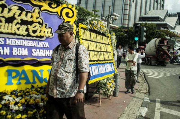 A man looks at floral tributes at the scene of a bomb blast at a police post in Jakarta, Indonesia, on 15 January 2016. (Photo: AAP).