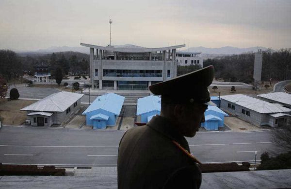 Korean People's Army Lt. Col. Nam Dong Ho is silhouetted against the truce village of Panmunjom at the Demilitarized Zone (DMZ), which separates the two Koreas, in Panmunjom, North Korea. (Photo: AAP).
