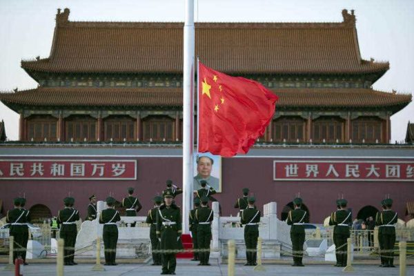 Chinese paramilitary policemen perform a flag-lowering ceremony near a portrait of Mao Zedong on Tiananmen Gate in Beijing, Monday, 9 March 2015. (Photo: AAP).
