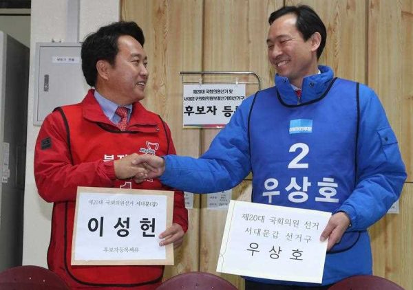 Lee Sung-hun, a candidate of the ruling Saenuri Party, and Woo Sang-ho, a candidate of the main opposition Minjoo Party of Korea, shake hands after registering for the general elections at a district election committee office in the south eastern city of Daegu, South Korea, 24 March 2016. (Photo: AAP).